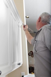 man in kitchen painting cabinet trim