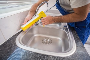 Plumber putting filling in between tiles of a kitchen remodel.